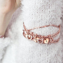 Close up of rose gold diamante heart charm personalised bangle set worn by model