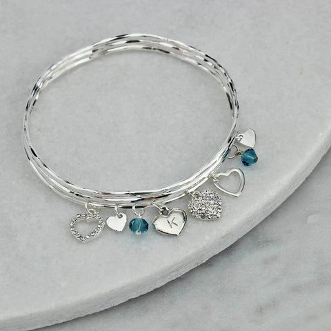 These sparkly heart charms hanging from our signature hammered bangles s...