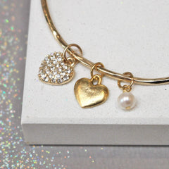 Close up of gold bangle with diamante heart and additional pearl