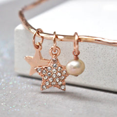 Close up of rose gold personalised bangle with diamante star and added freshwater pearl
