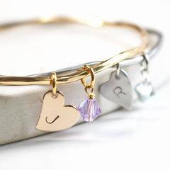 Close up of gold and silver personalised bangles with heart charms and Swarovski crystal