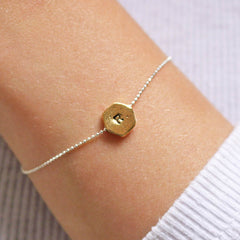 Hand stamped R hexagon bracelet in gold worn by model